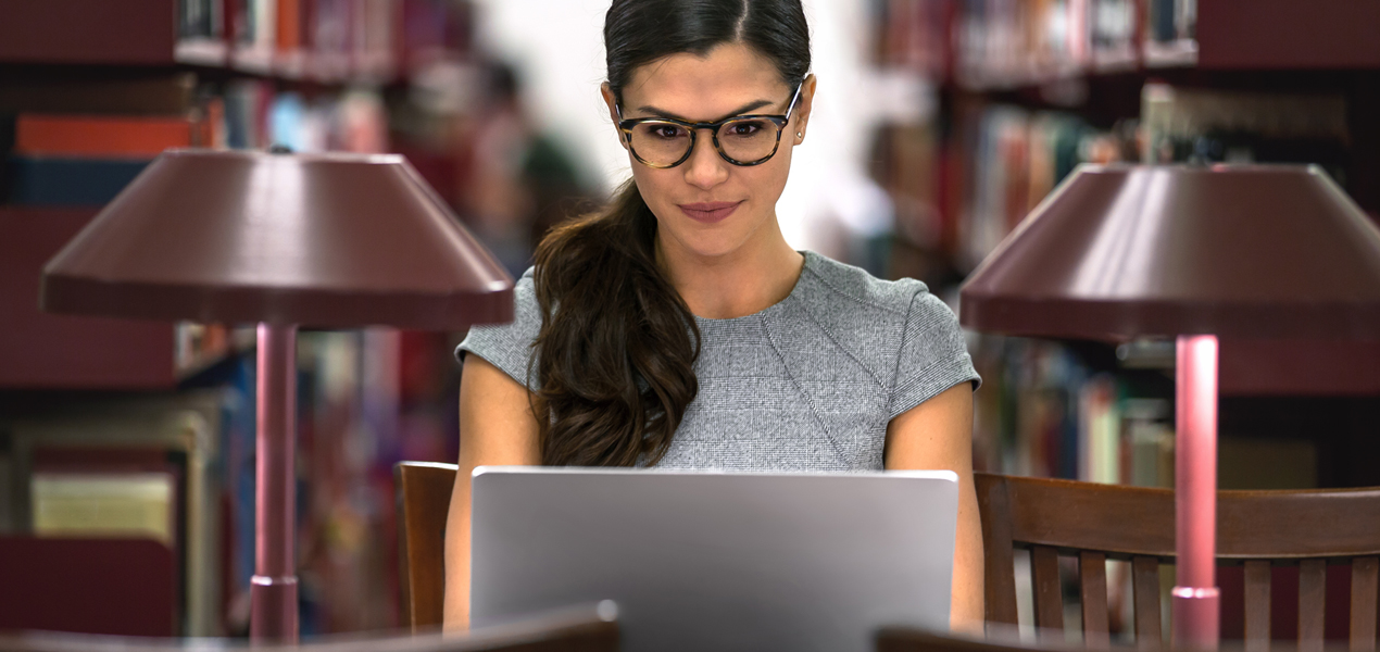 University student studying on a laptop in a library.