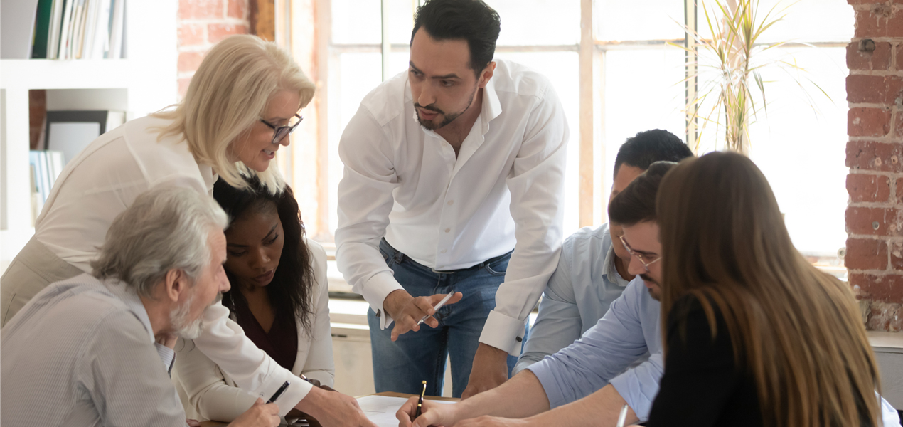 Employees gathered around a table sharing ideas at a meeting.