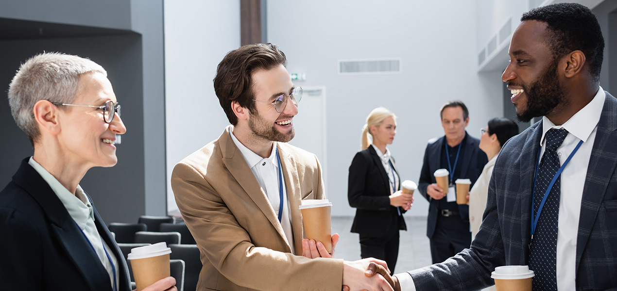 Delegates with coffee cups in hand chatting with each other.