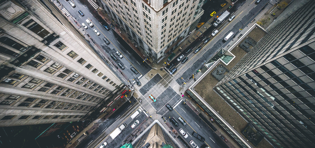 Overhead view of city intersection surrounded by tall buildings.
