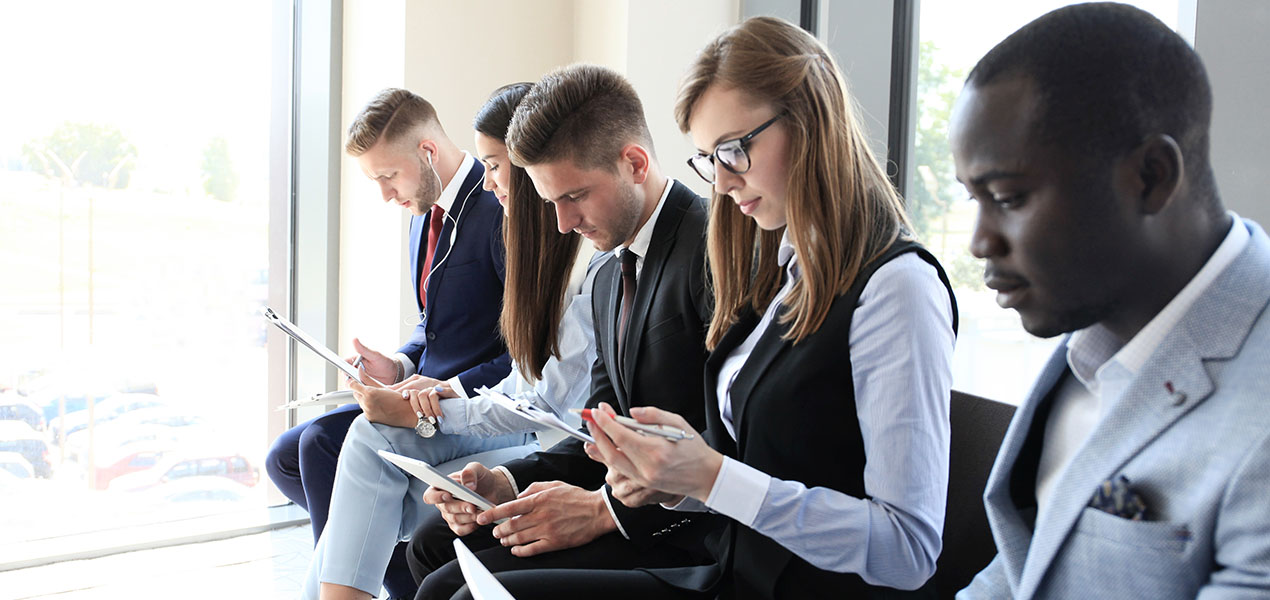 Des personnes assises en rangée, occupées à consulter leurs téléphones portables